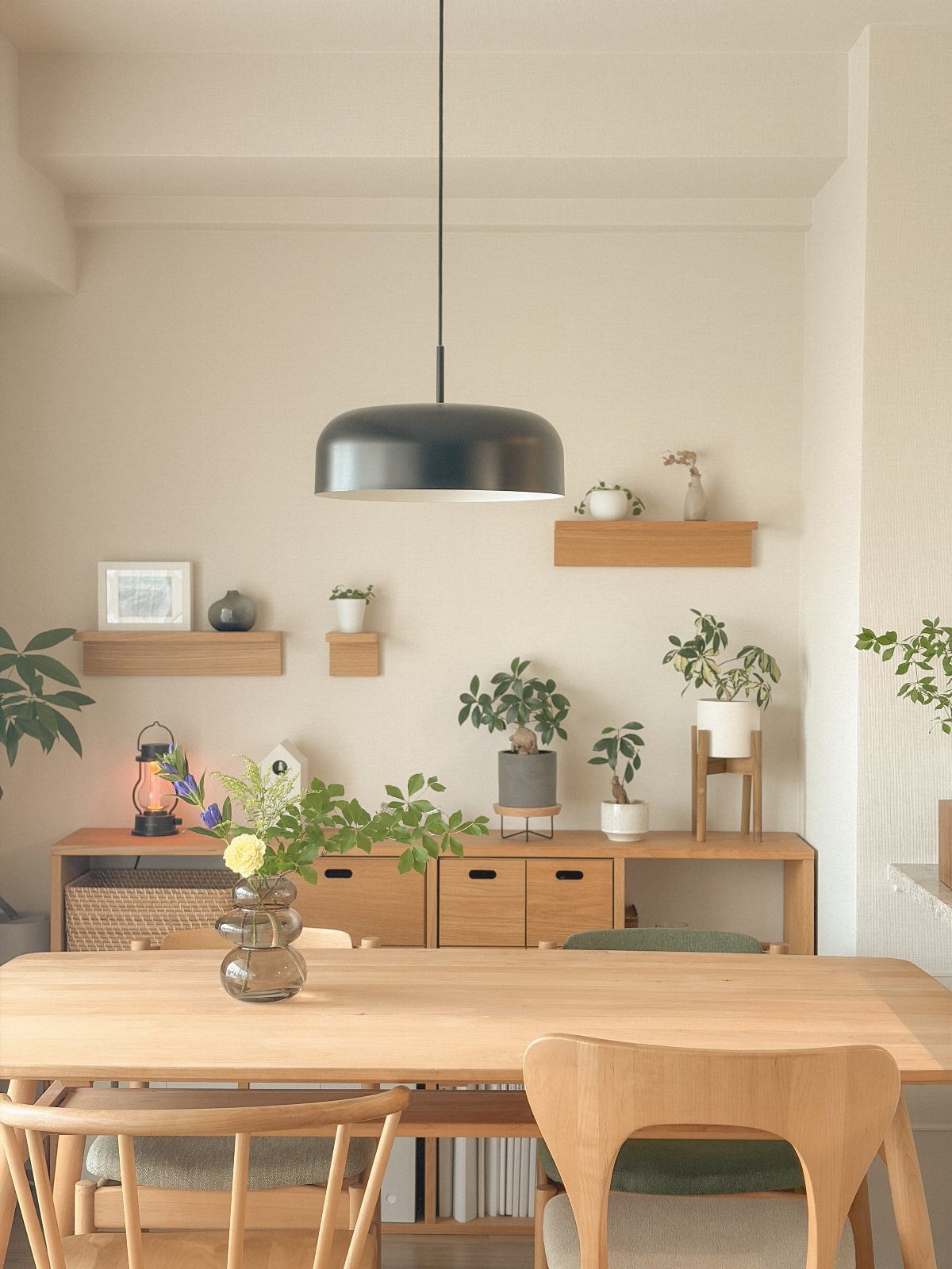 Minimalist Japanese style dining room with light wood furniture and green potted plants.