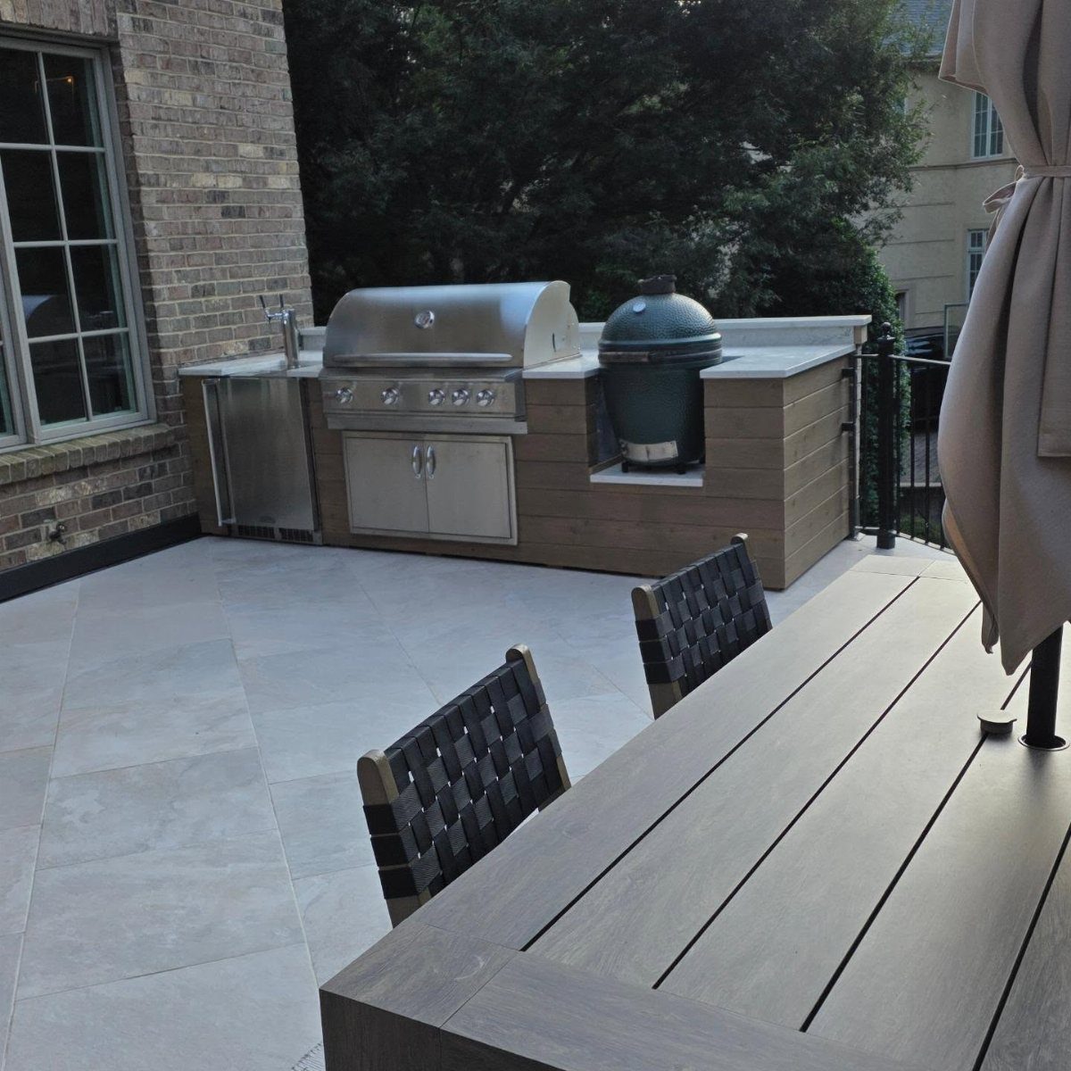 Built-in outdoor BBQ grill station with stainless steel grill and ceramic cooker on patio