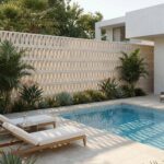 Rectangular swimming pool with white lounge chairs and a decorative lattice wall background.